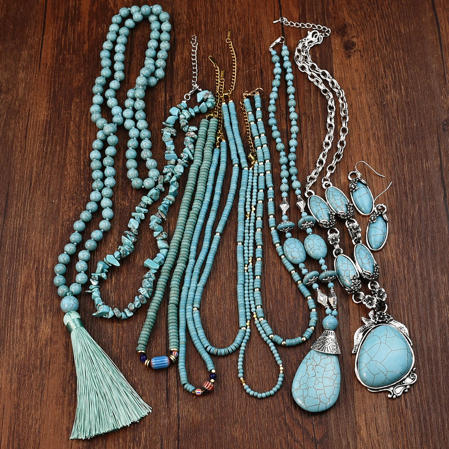A collection of turquoise beaded necklaces with tassels and silver-tone pendants on wood