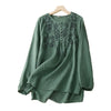 Green long sleeve cotton linen top with floral embroidery hanging on a wooden hanger