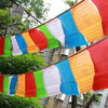 Colorful Tibetan prayer flags strung up outdoors among green trees