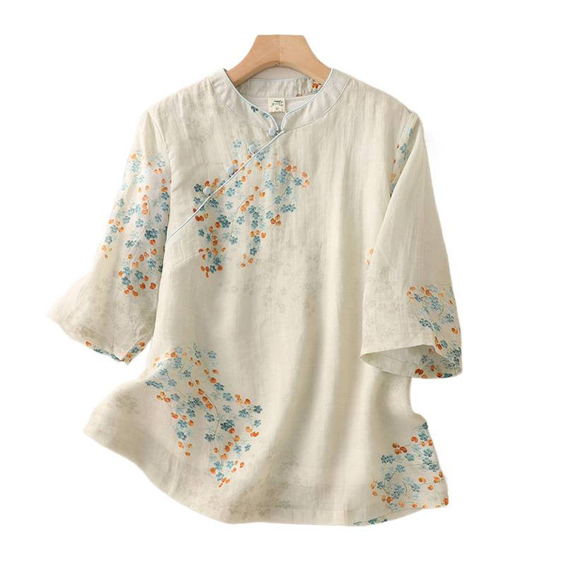 Close up of cream shirt fabric with blue flowers orange leaves and white frog buttons
