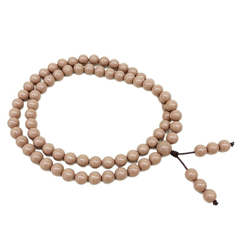 Coiled light brown herbal scented prayer beads on a white background