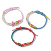 Three colorful hand-woven bracelets with koi fish charms on a white background
