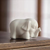 A small white ceramic elephant statue sitting on a wooden surface