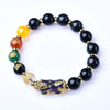 Close up of a black obsidian bracelet with a color-shifting Pixiu charm