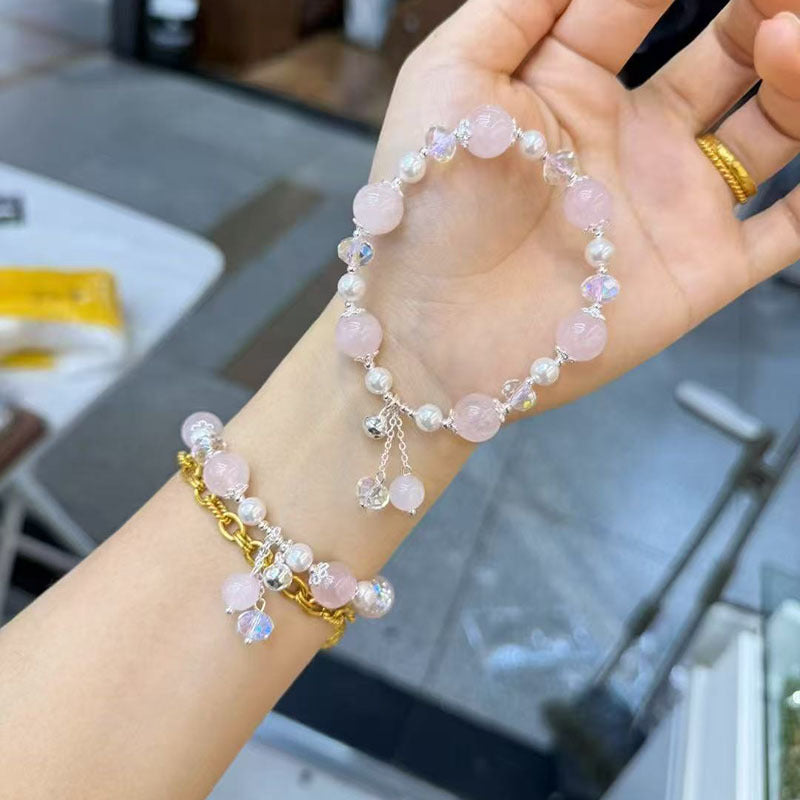 Close-up of a wrist wearing a pink crystal bead bracelet with a flower charm and gold chain accent.