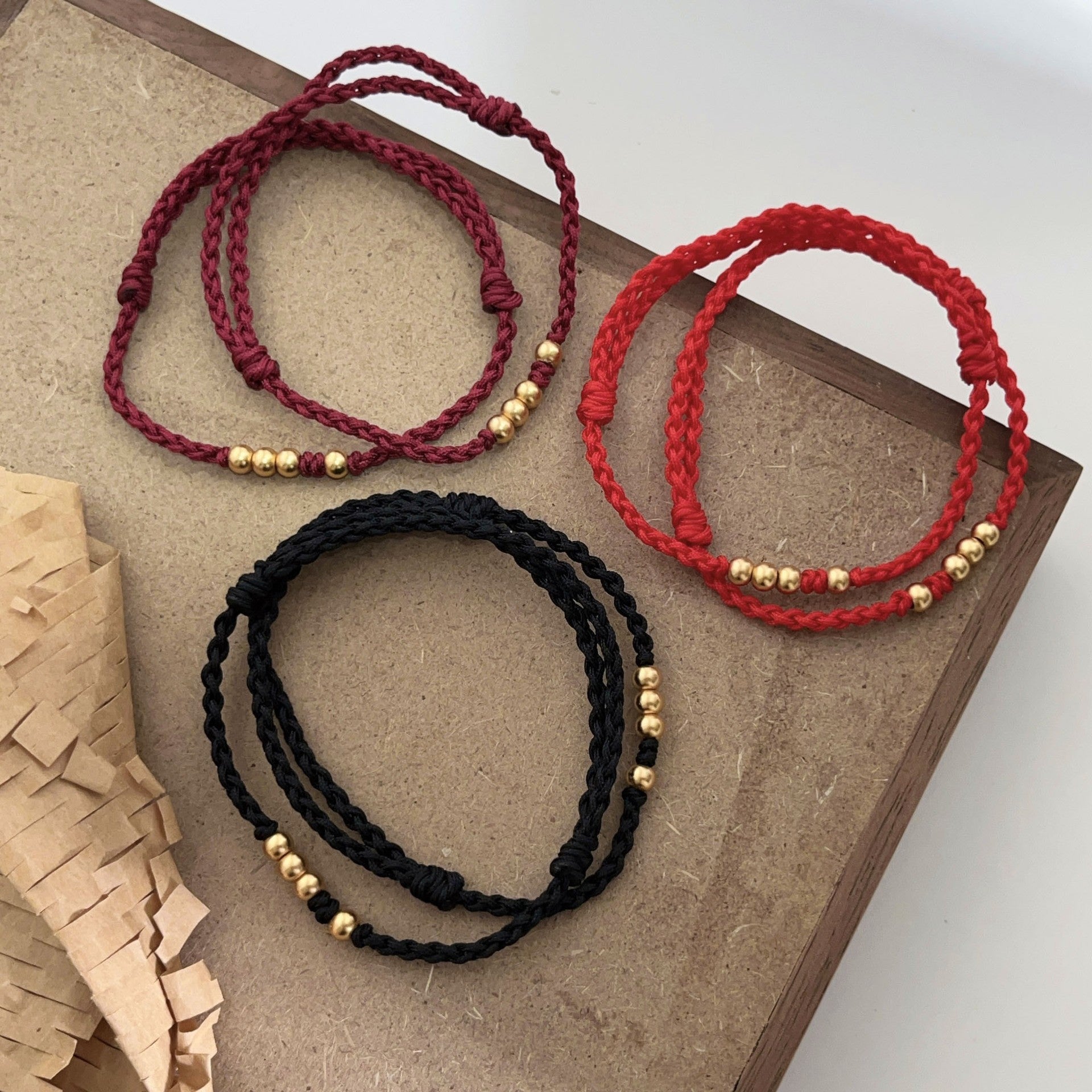 Three braided cord bracelets in red, wine red and black with silver beads