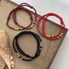 Three braided cord bracelets in red, wine red and black with silver beads