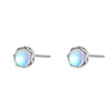 Close up of small round moonstone stud earrings in silver settings on a blue surface