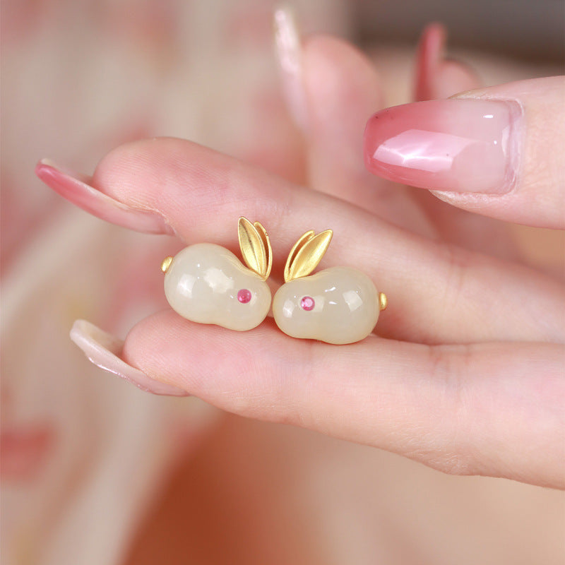 Close up of white jade rabbit stud earrings held in hand