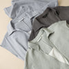 Three folded sleeveless dresses in blue, brown, and green showing the collar detail