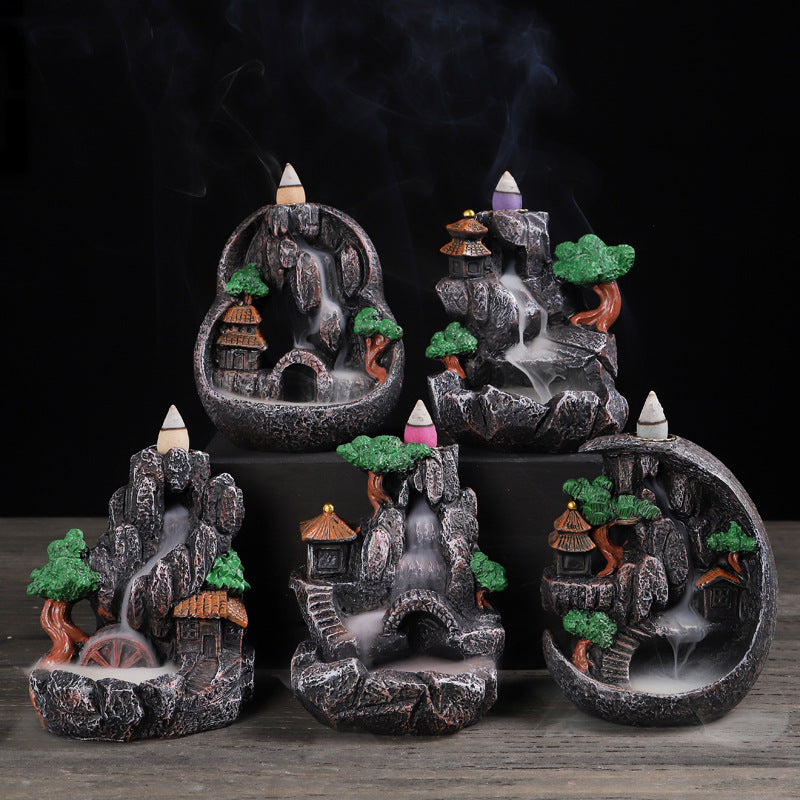 Five mini resin backflow incense burners with landscape designs on a wooden surface