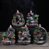 Five mini resin backflow incense burners with landscape designs on a wooden surface