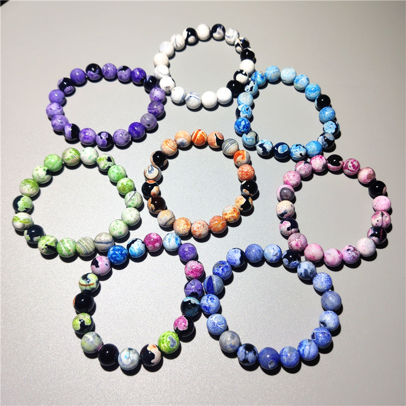 Several colorful galaxy agate bracelets arranged on a white surface