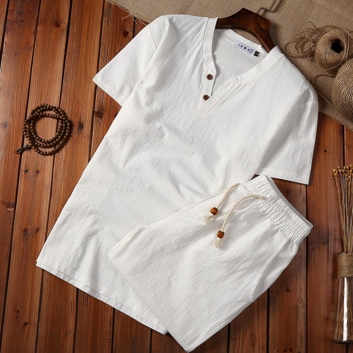 White cotton linen men's meditation cloth set with short sleeve top and shorts on wood floor