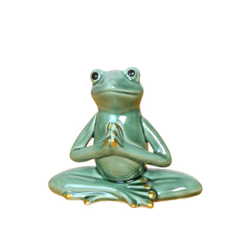 Green ceramic frog statue sitting in a meditation yoga pose with hands together