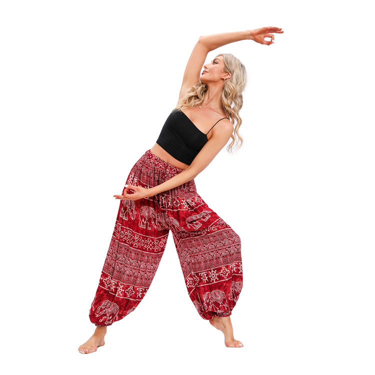 Woman wearing red elephant print harem pants in a yoga pose
