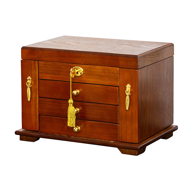 A vintage style dark wood jewelry box with gold hardware and a tassel lock on a table
