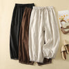 Three pairs of retro embroidered drawstring pants in black, brown, and beige laid flat on a beige background