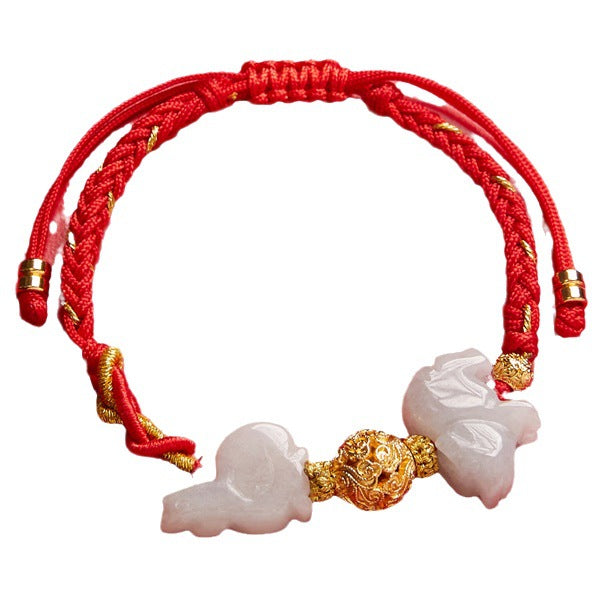 Close up of a red string bracelet with white jade charms and a gold bead