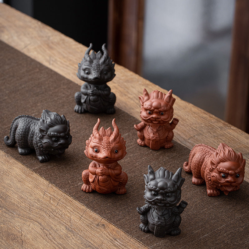 A collection of small purple clay tea pets shaped like dragons and mythical beasts on a wooden table