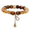 Close up of a beaded bracelet with brown tiger eye and yellow citrine beads featuring a hanging gourd charm