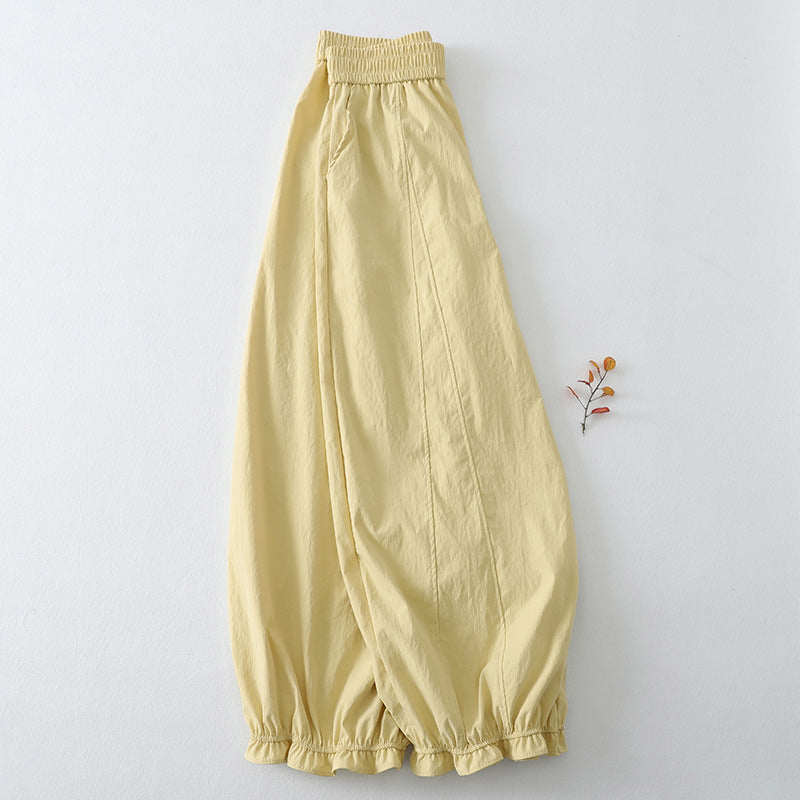 Yellow cotton linen harem pants with ruffled hem laid flat on white background