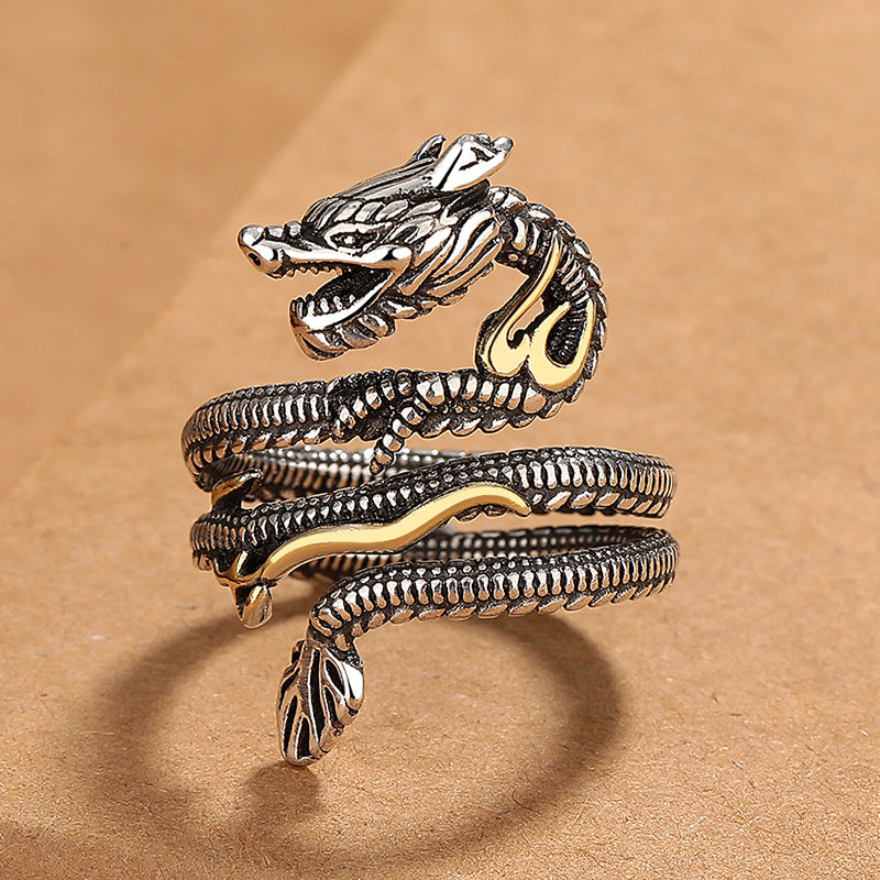 Close up of a silver tone copper dragon ring with gold accents on a brown background