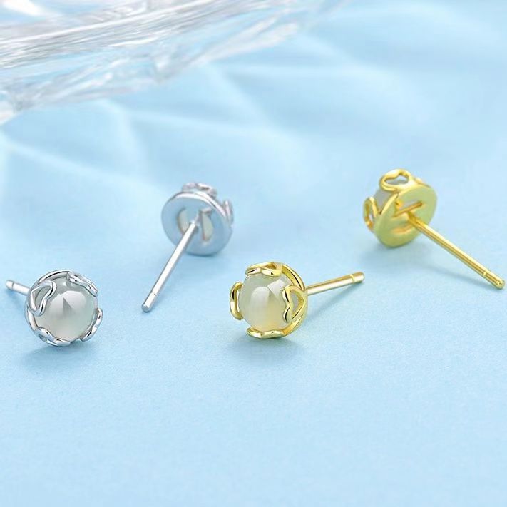 Close up of small heart shaped jade stud earrings in gold and silver tones
