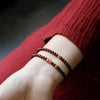 Close up of a wrist wearing a double wrap wine red glass bead bracelet with a gold accent
