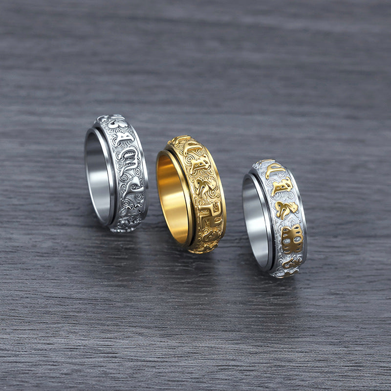 Three titanium steel rings with engraved mantras sitting on a dark wood surface