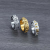 Three titanium steel rings with engraved mantras sitting on a dark wood surface