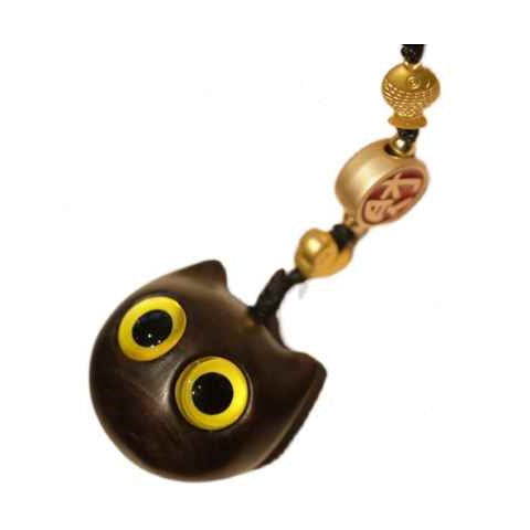 Close-up of a dark brown wooden cat head charm with large yellow eyes.