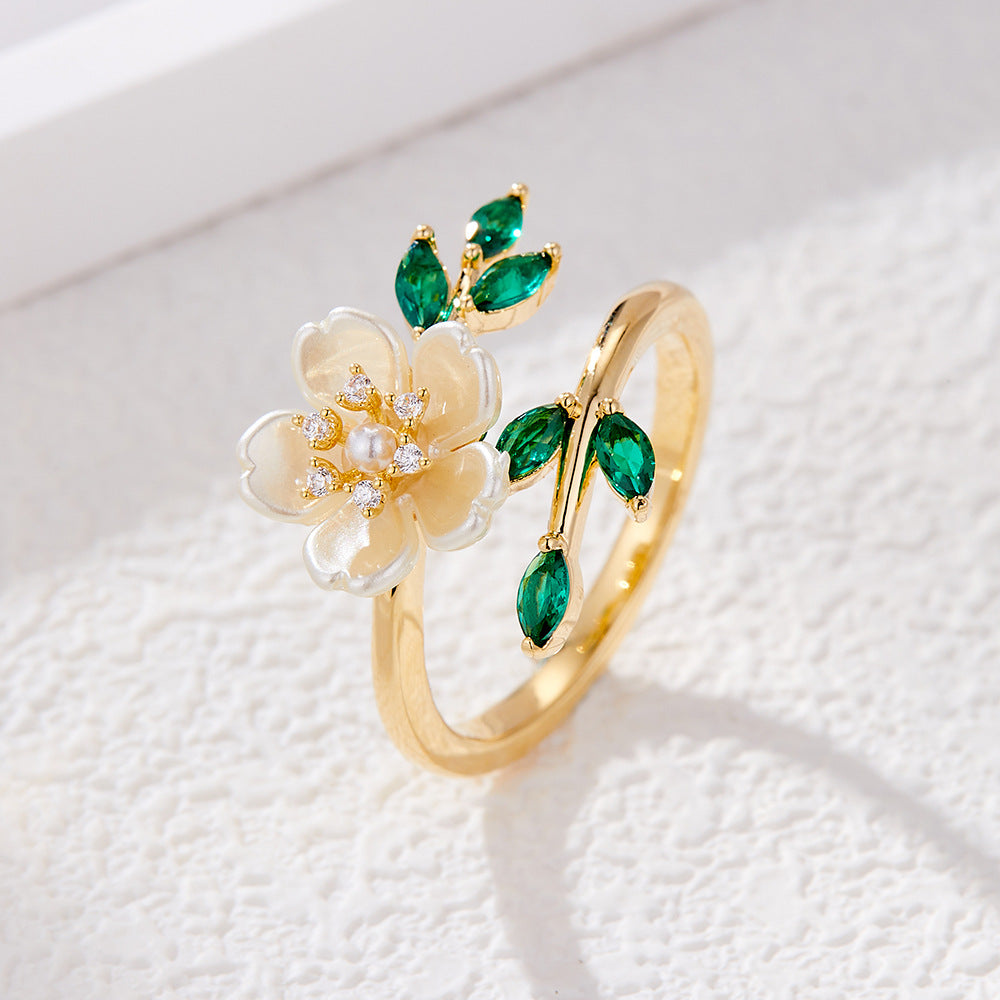 Gold tone open ring with white flower and green leaves
