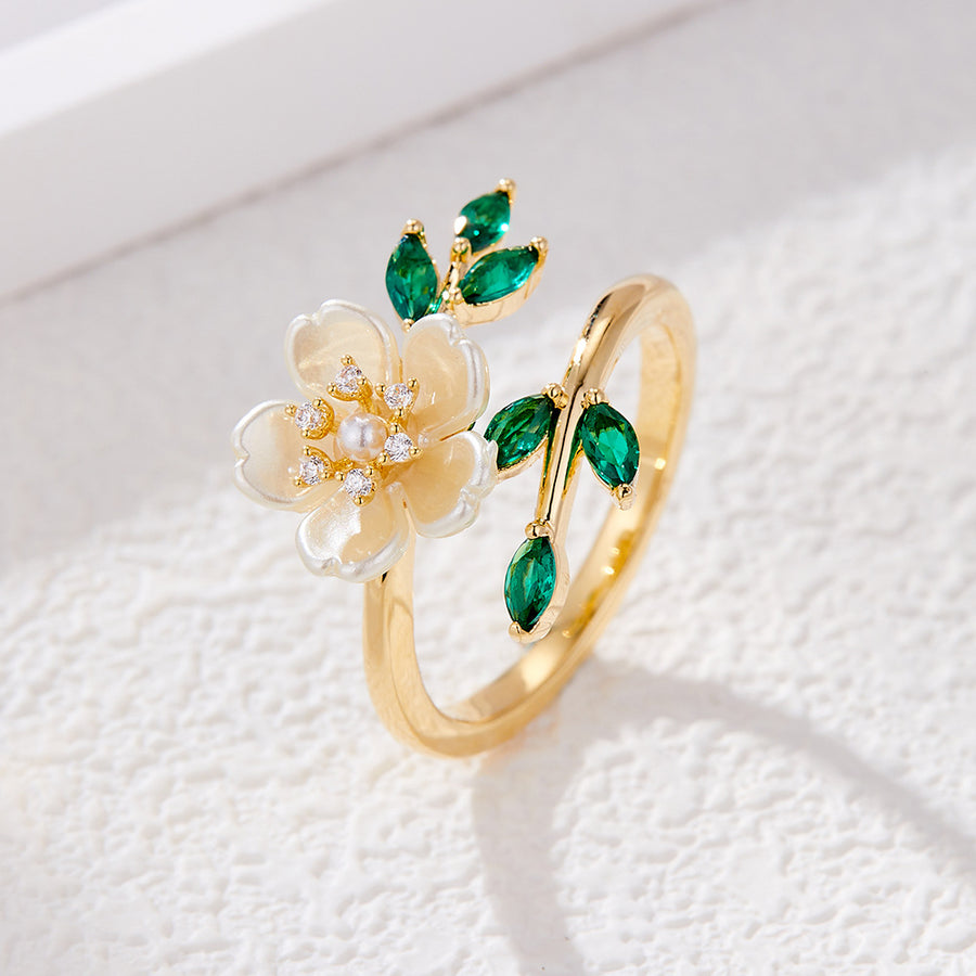 Gold tone open ring with white flower and green leaves