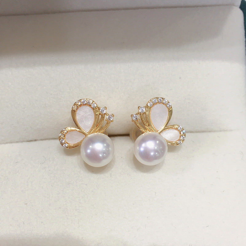 Close up of gold butterfly stud earrings with white pearls