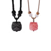 Two carved lion dance pendants, one black obsidian and one pink stone, displayed side by side