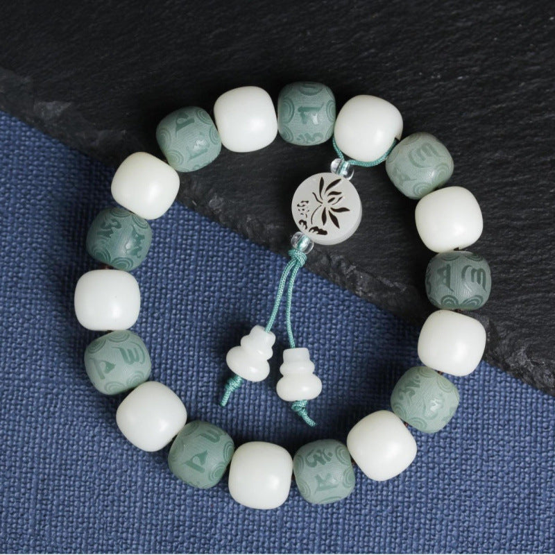 Close up of white and green gradient bodhi seed bracelet with carved mantra charm