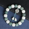 Close up of white and green gradient bodhi seed bracelet with carved mantra charm