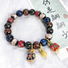 Multi-colored glass bead bracelet with gold-tone pendants on a white background