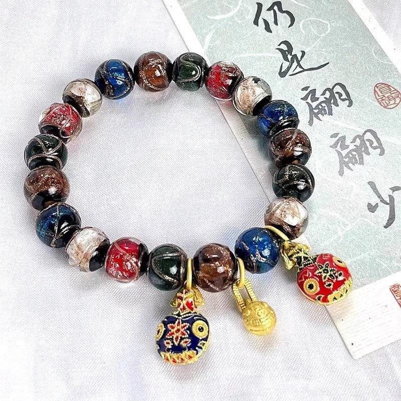 Multi-colored glass bead bracelet with gold-tone pendants on a white background