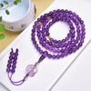 Purple amethyst 108 bead mala bracelet coiled on a white surface