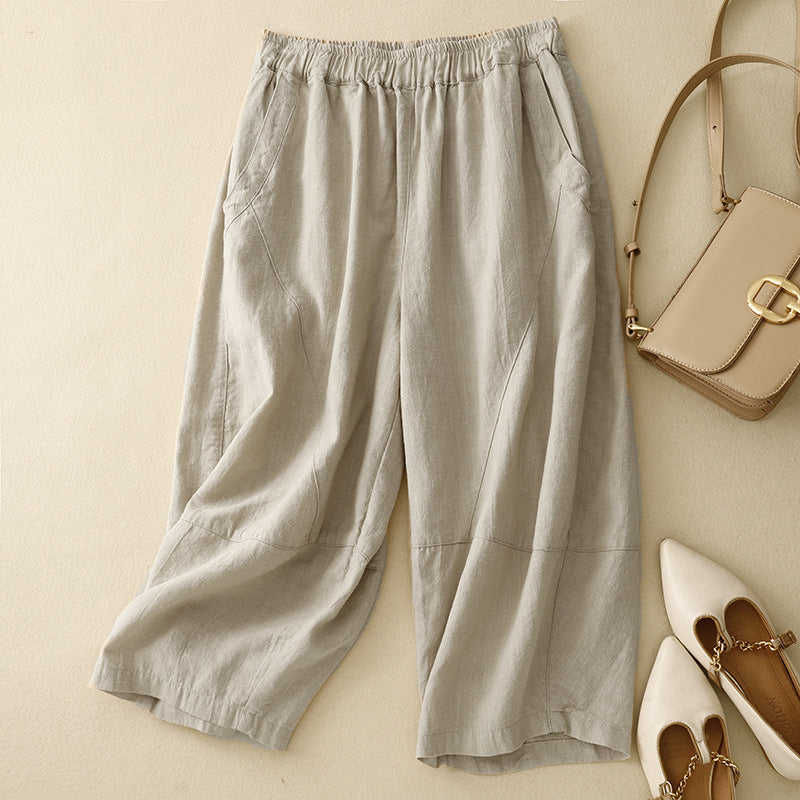 Flat lay of beige linen wide-leg harem pants with elastic waist next to a handbag and shoes