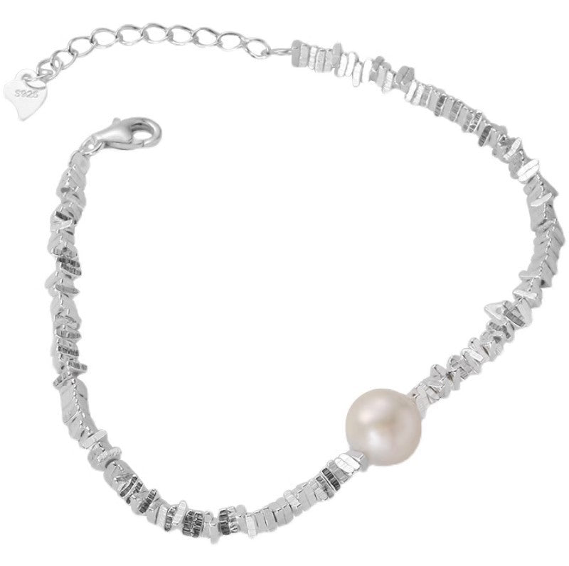 Close up of a silver tone bracelet with irregular beads and one pearl on a wrist