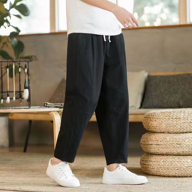 Man wearing black loose cotton linen pants with pockets standing indoors