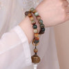 Weathered bodhi seed mala beads draped over a hand showing brown and green colors