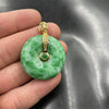 Close-up of a round green and white jade peace buckle pendant held in hand