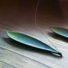 Green ceramic incense burner shaped like a leaf holding a stick
