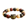 Wooden beaded bracelet with a carved black cat face charm on a yellow background