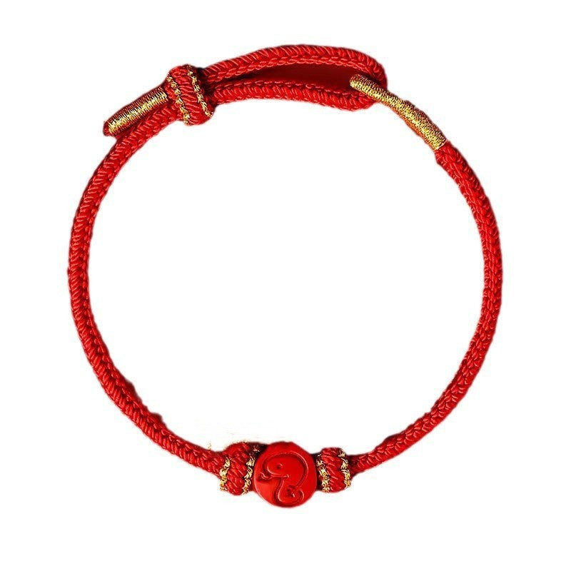 Red woven bracelet with gold accents and a red zodiac charm on a white background