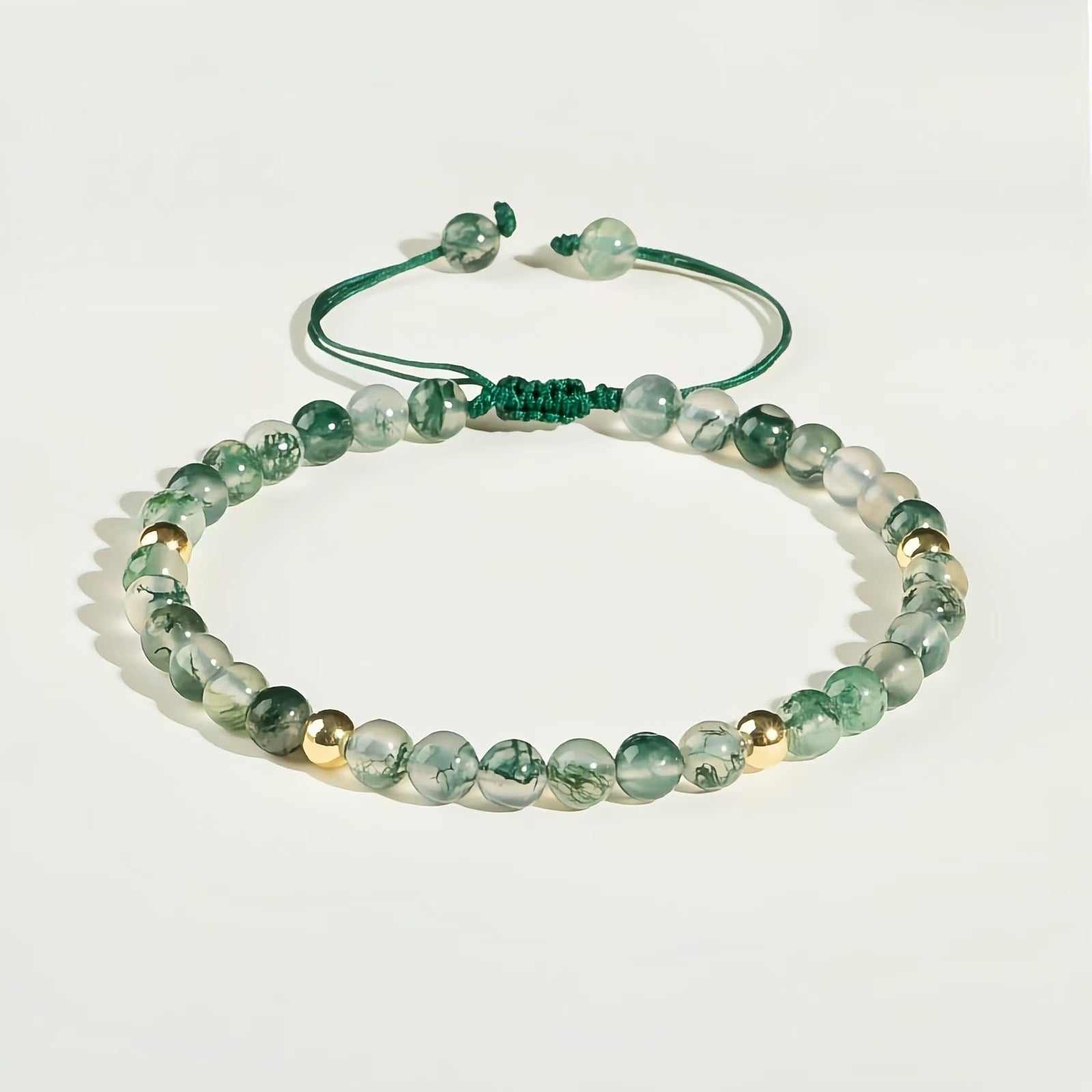 Green moss agate beaded bracelet with gold accents on white background